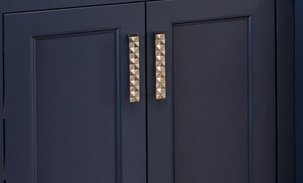 Closeup of navy cabinetry by Laslo Custom Kitchens with textured silver hardware,