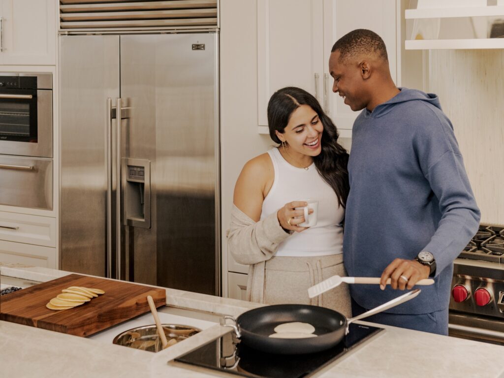 A couple hugs while cooking breakfast