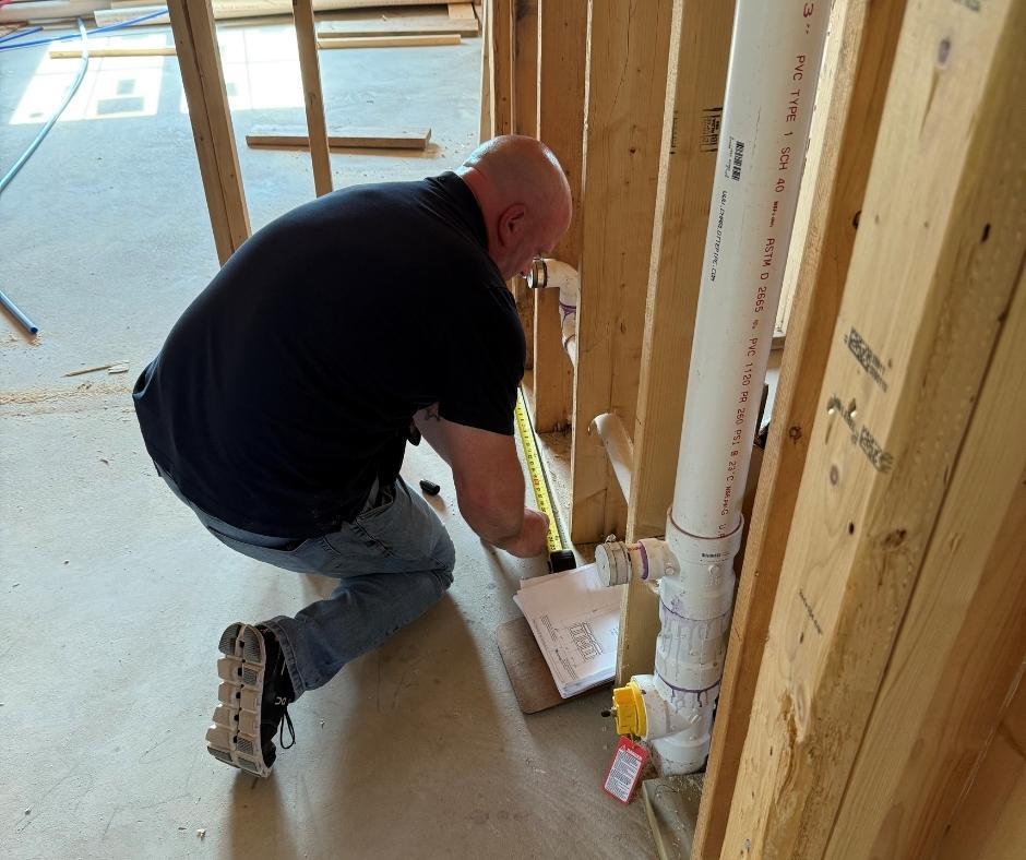 A man does measurements in a kitchen under construction.