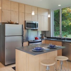 A kitchen with a small peninsula and 2 light wooden barstools.