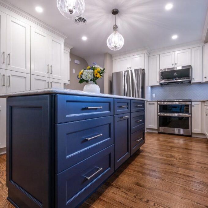 An Indigo kitchen island with white counter in a kitchen with white cabinets.