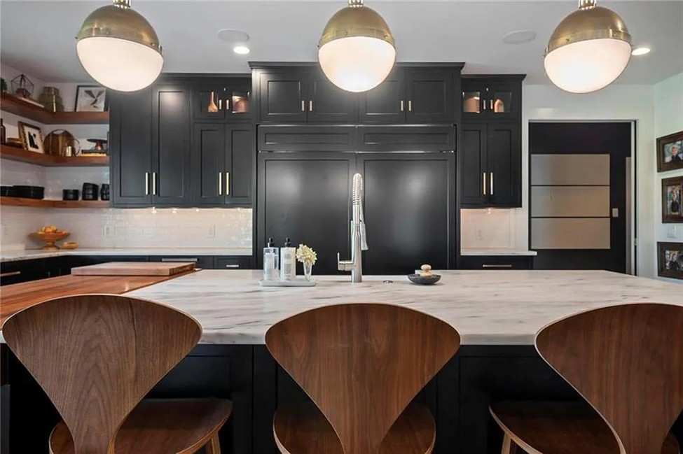 A kitchen black cabinets and wood barstools.
