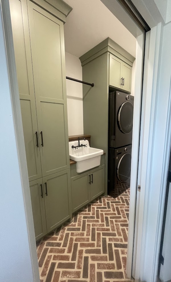 A laundry with green cabinets and brick floor.