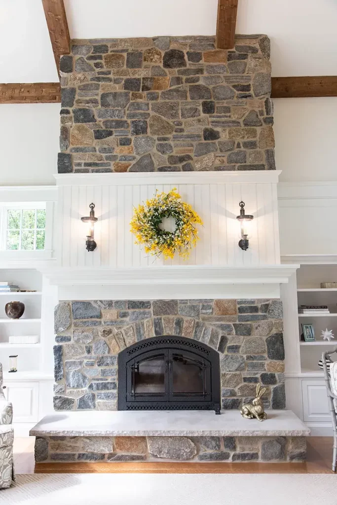 A custom stone fireplace that is built-in to the custom cabinets that are surrounding it.