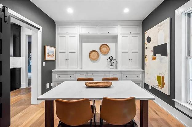 An office with white built-in cabinets and a table with white top and think wooded legs.
