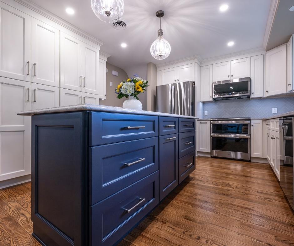 An Indigo kitchen island with white counter in a kitchen with white cabinets.