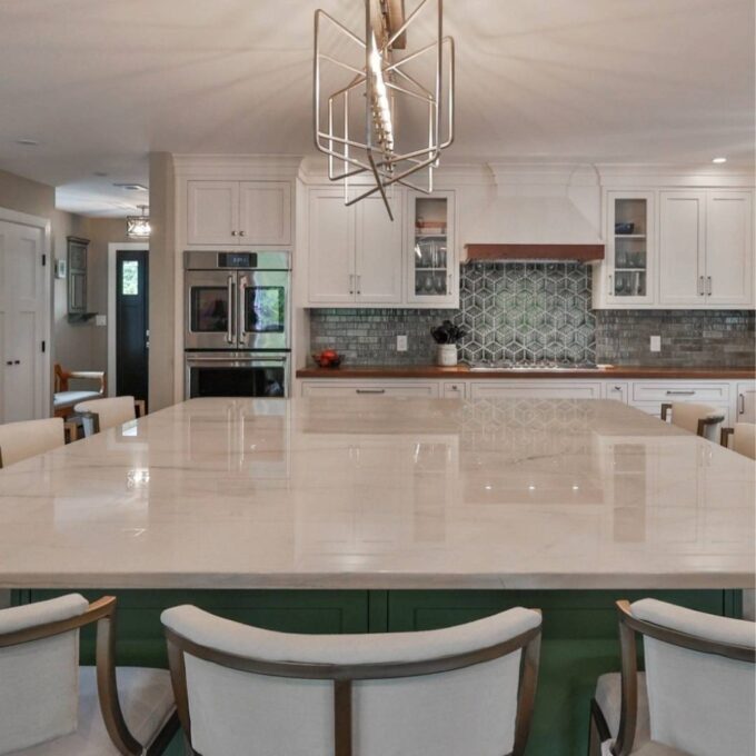 A kitchen with light maple cabinets and a green island.
