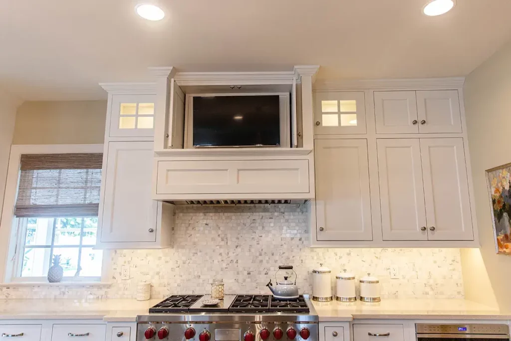 Custom white kitchen cabinetry with hidden television cabinet.