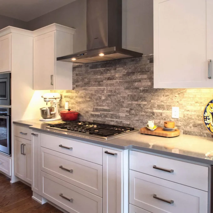 A kitchen with white cabinets and a stove