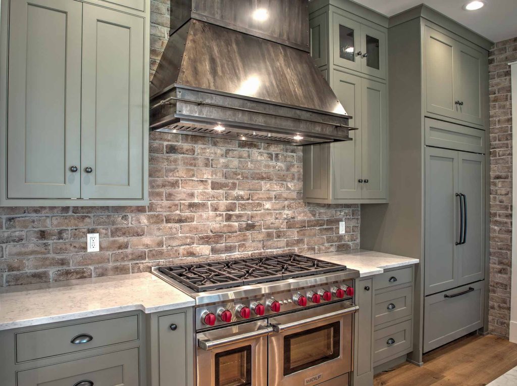 A kitchen with metal range hood over the stove and oven
