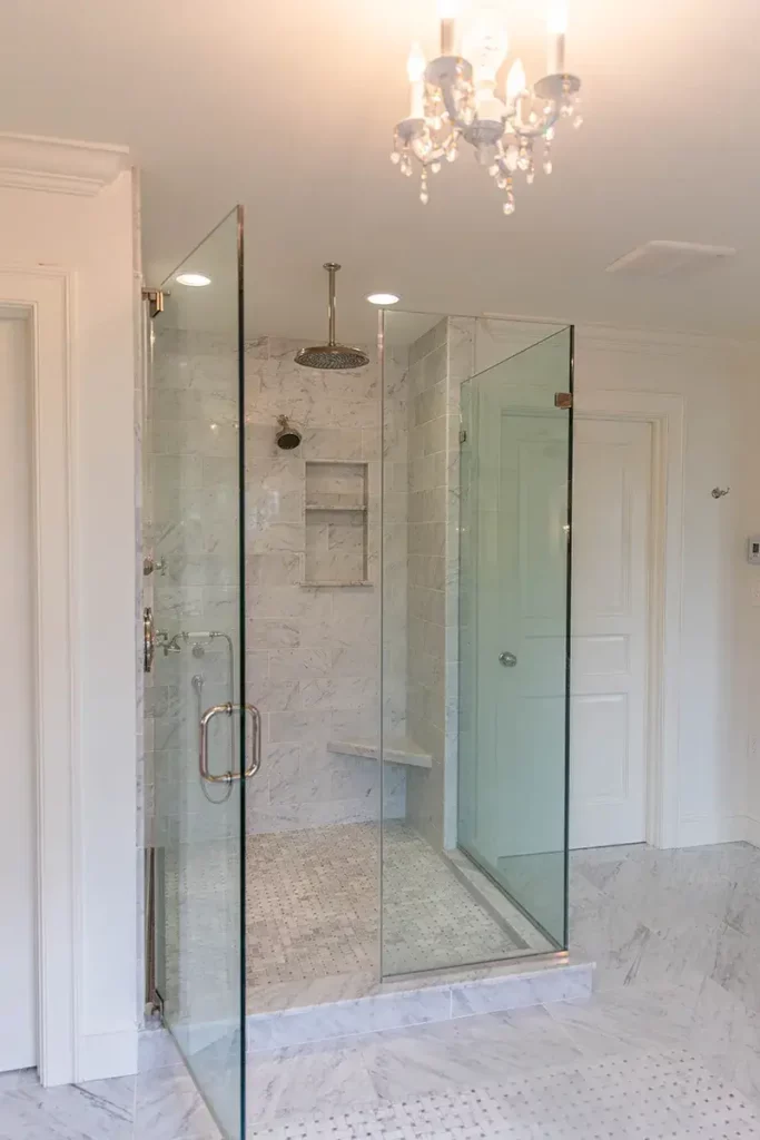 walk-in shower with marble tile and glass surrounding panels