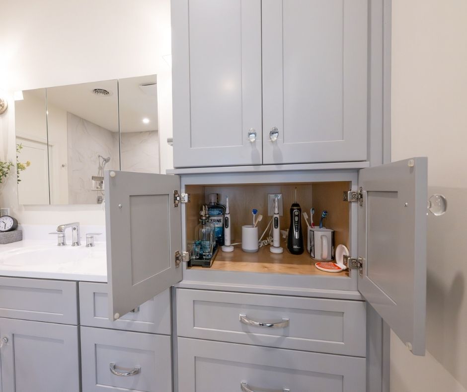 A gray bathroom cabinet is open to products inside.