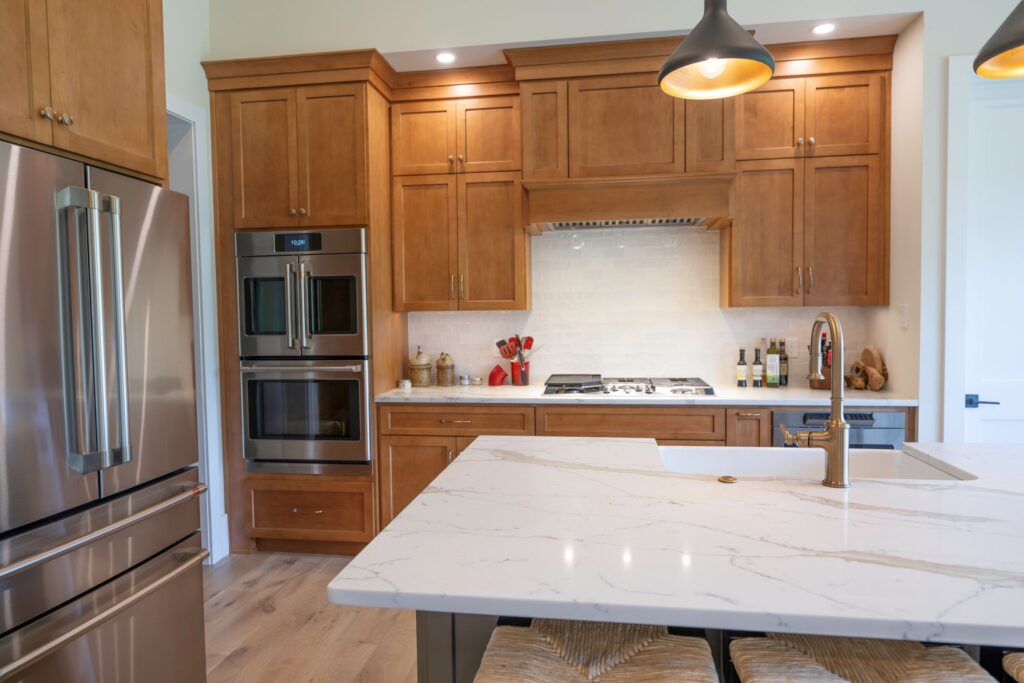 Symmetrical view looking across the gold-veined quartz countertop of the center island toward the custom wood range hood and stacked molding.