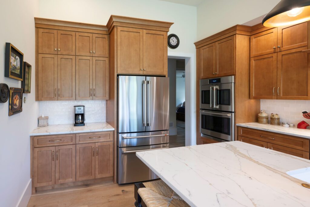 Built-in stainless steel refrigerator surrounded by full-height hard maple pantry cabinetry with deliberate crown molding profiles.