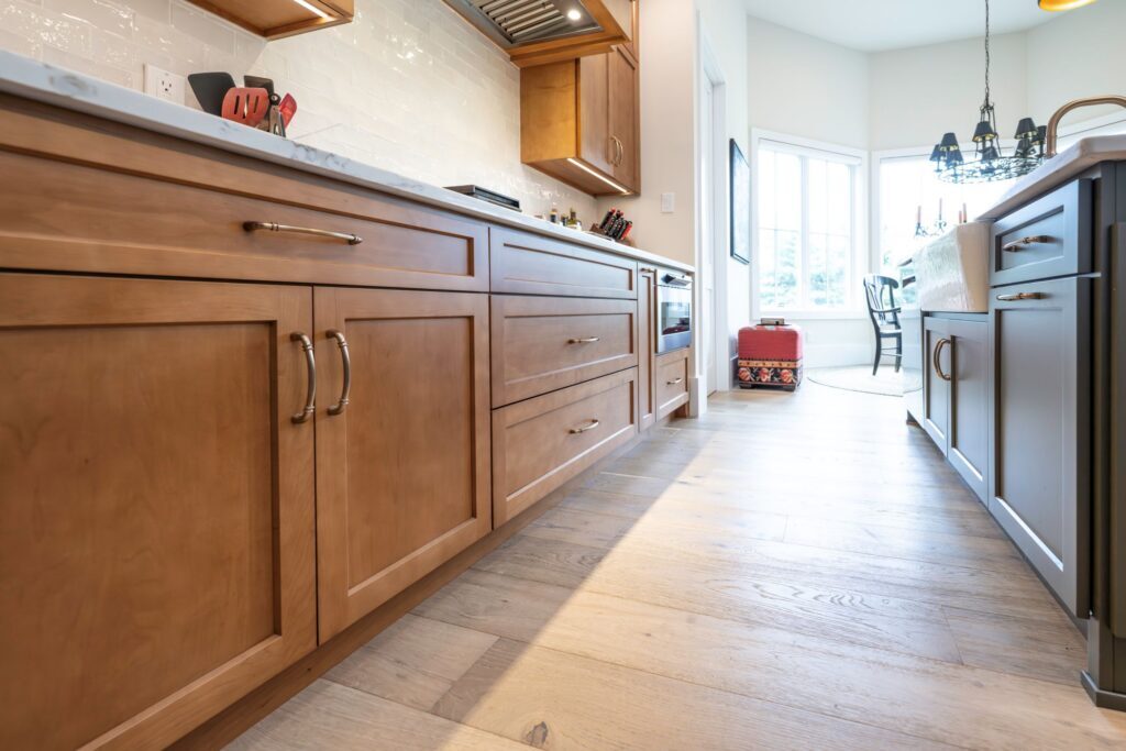Low-angle perspective showing the clean aisle between the hard maple perimeter cabinetry and the painted center island.