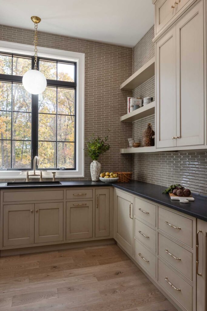 Butler's kitchen window and sink area with painted inset cabinets, open shelves, and drawer storage.