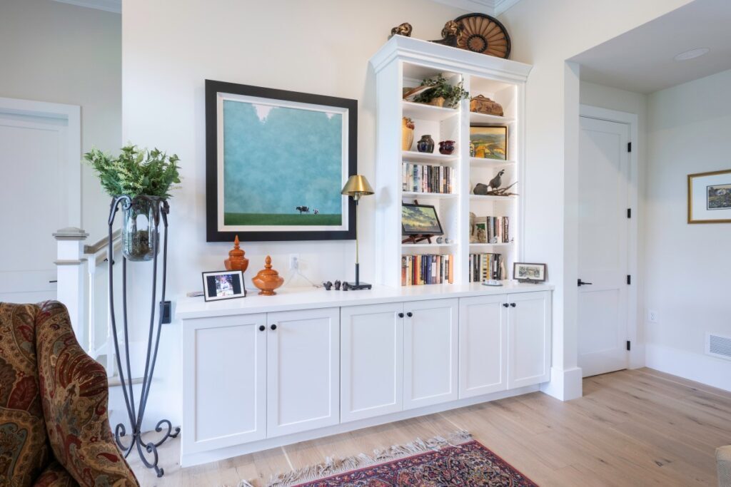 Angled view of a Frost painted maple bookcase with adjustable shelves, black hardware, and stacked crown molding.
