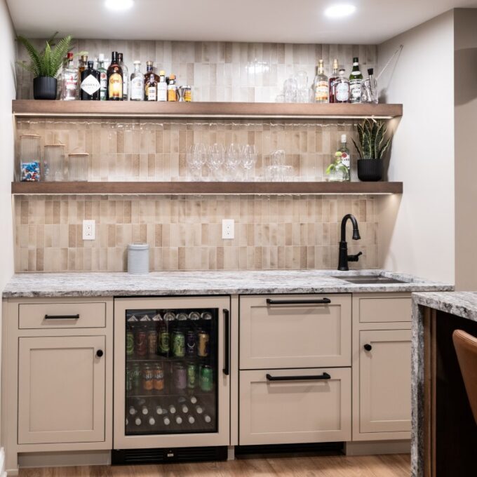 Center Valley wet bar with Tyler Gray flush inset cabinetry, Blue Dunes granite, beverage refrigeration, sink, and illuminated floating shelves.