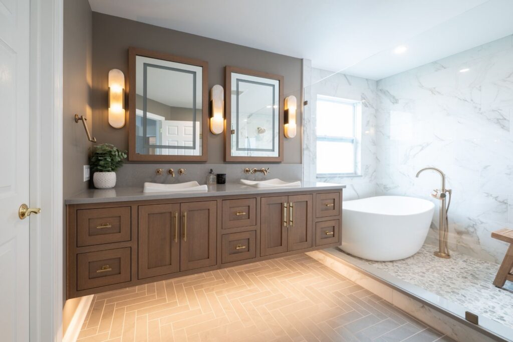 Easton primary bathroom with a Sesame-stained Rift Cut White Oak double vanity, vessel sinks, freestanding tub, and glass shower partition.