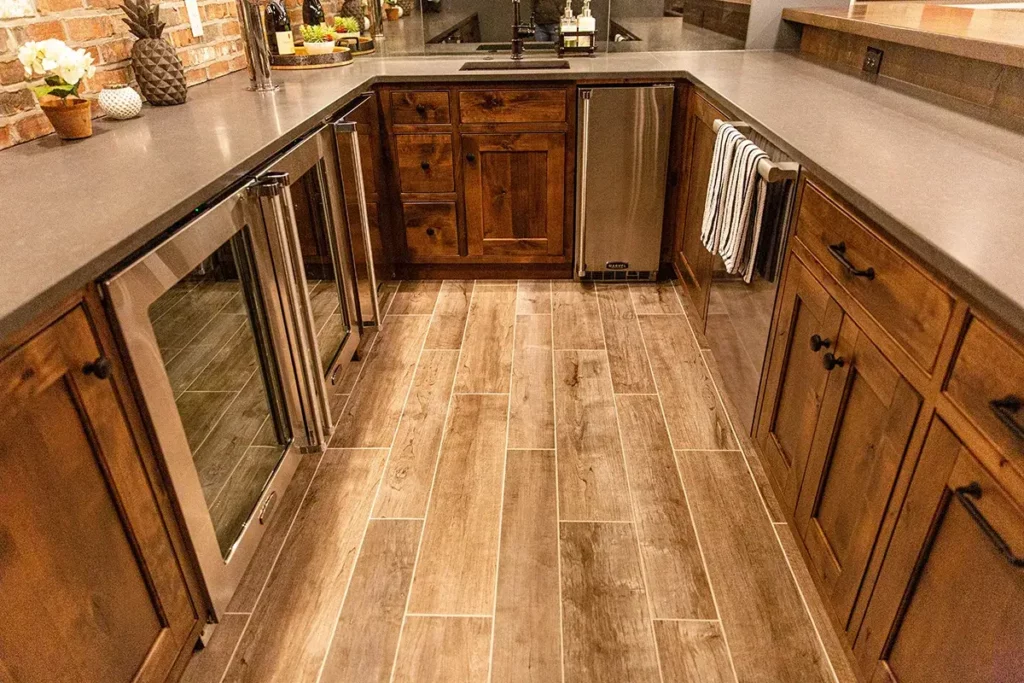 A custom bar that has premium stainless steel appliances and tile flooring that looks like wood planks