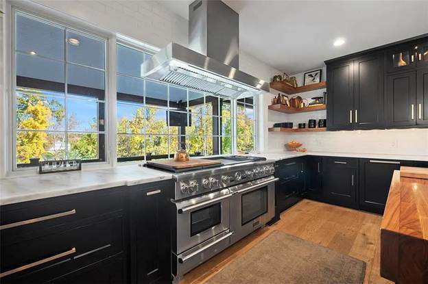 A kitchen with a stainless hood and black cabinets.