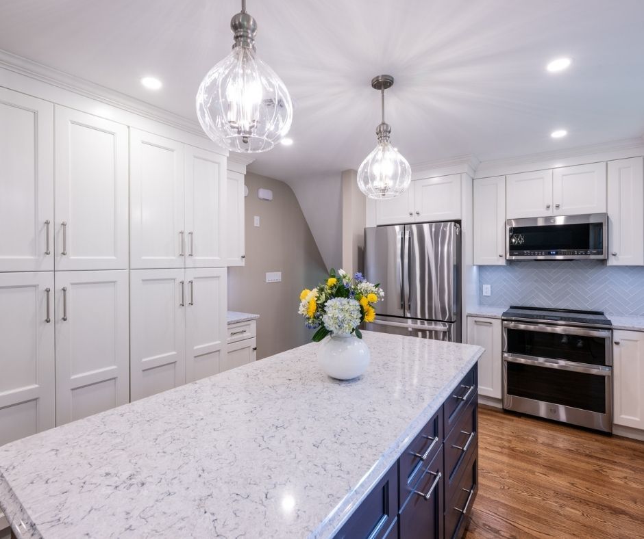 A kitchen with white wall cabinets and a large blue island.